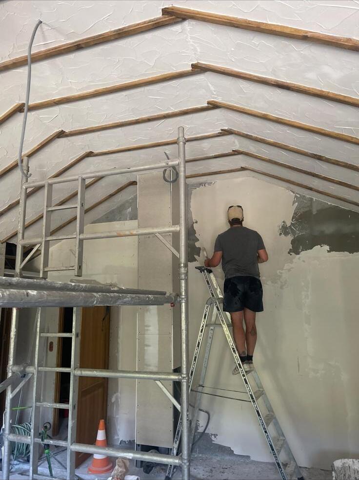 Plasterer hand-skimming a vaulted internal wall from a scaffold tower